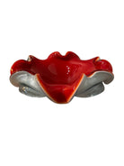A Murano art glass bowl featuring a vibrant red interior encased in white glass, with a decorative ruffled edge. The piece is handblown, showcasing the Incamiciato technique.
