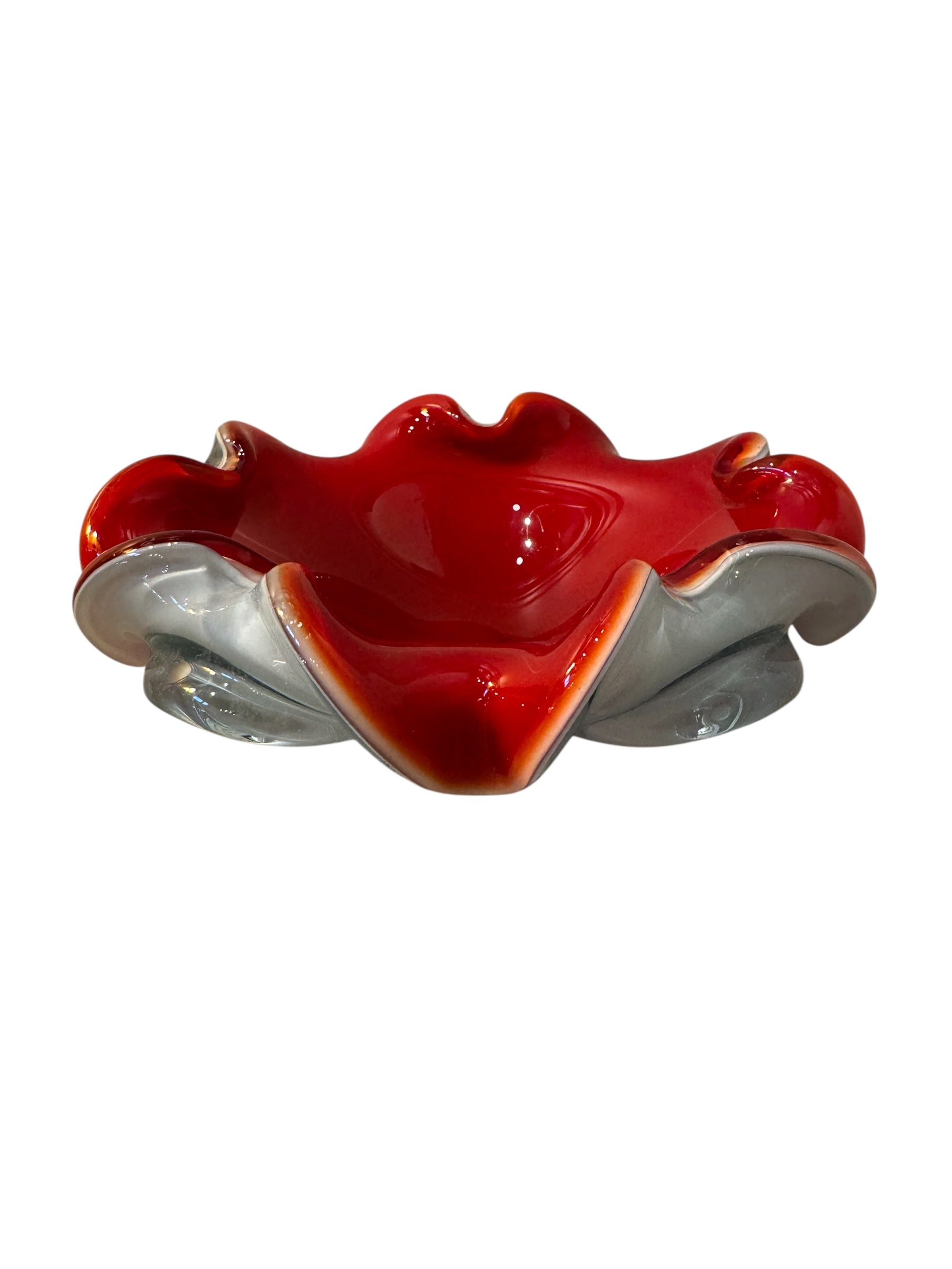 A Murano art glass bowl featuring a vibrant red interior encased in white glass, with a decorative ruffled edge. The piece is handblown, showcasing the Incamiciato technique.