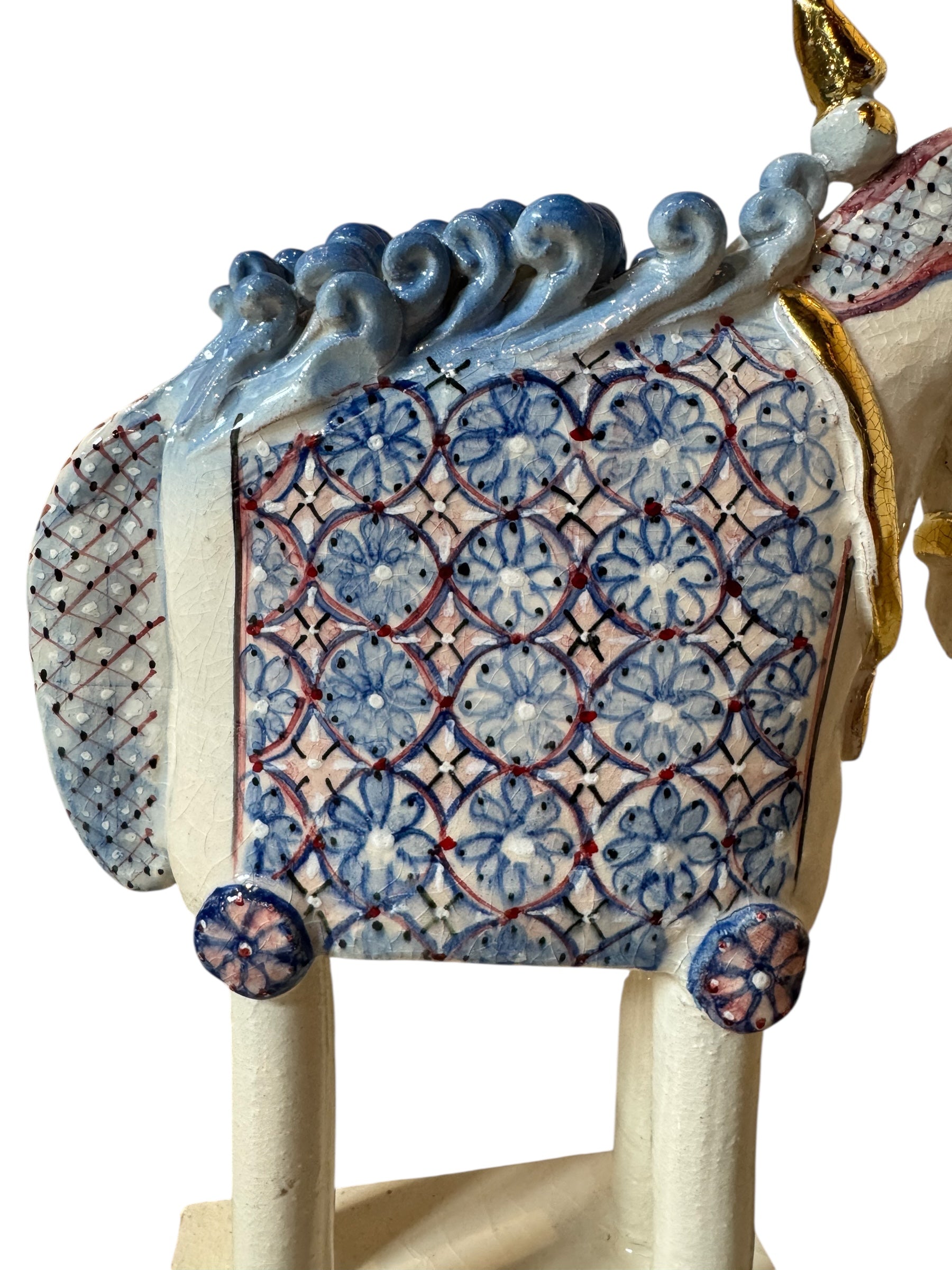 Ceramic horse by Domenico Pinto, featuring a white glazed body, geometric quilting on the saddle, a decorative crown with white and gold accents, and 24Kt gold detailing. The horse stands on four legs and is placed on a white base.