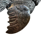 A pair of vintage, silver-plated brass fighting rooster figurines positioned in a confrontational stance against a white background. The rooster on the left is crouched low with its head down and tail feathers fanned high, while the rooster on the right stands more upright with its wings slightly flared. Both feature intricate feather detailing, a metallic patina showing hints of brass through the silver, and small, bright red glass eyes.