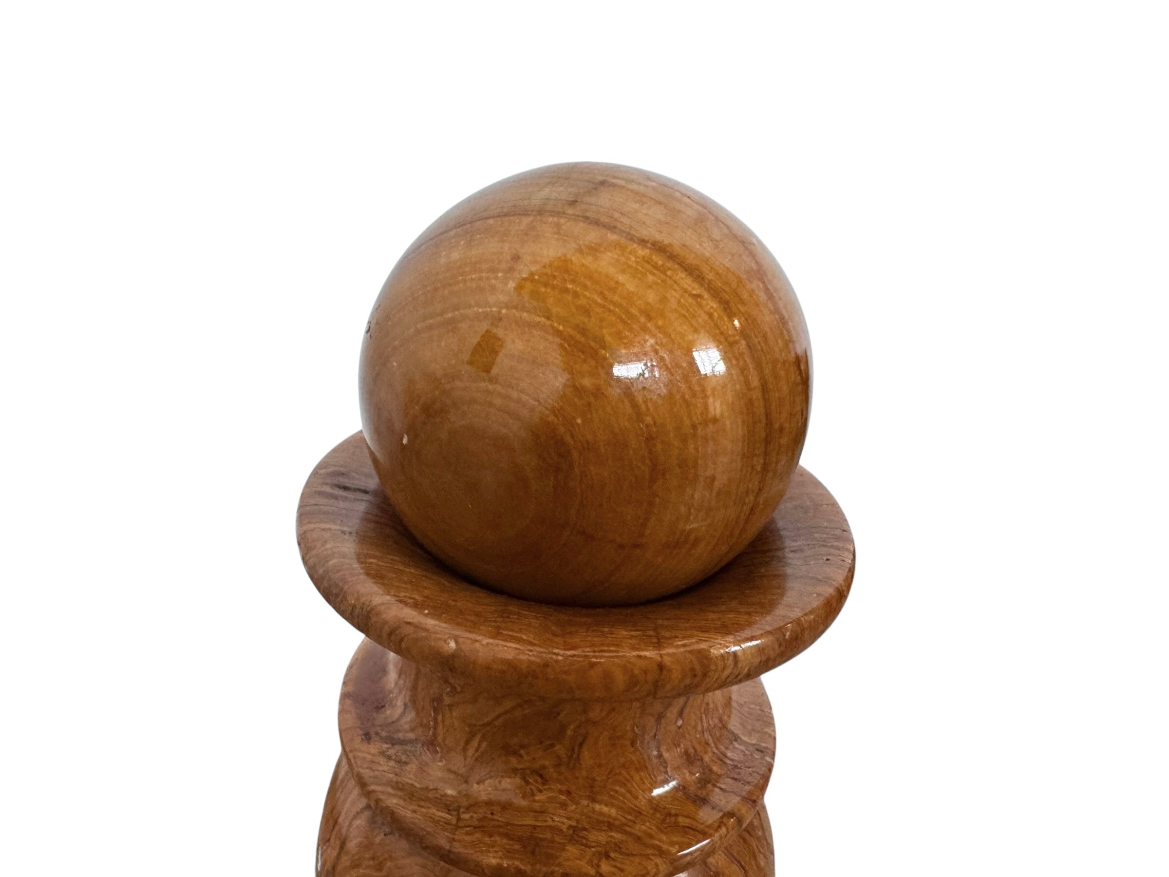 An elegant, hand-carved decorative vase made of polished Pakistani brown onyx. The vase features a classic, rounded urn shape with a tiered, flared neck and a solid matching spherical stone stopper resting on top. The stone displays rich, natural horizontal banding and swirling patterns in shades of honey, deep amber, rust-red, and cream. It stands on a small, integrated pedestal base against a clean white background, reflecting a high-gloss, mirror-like finish.