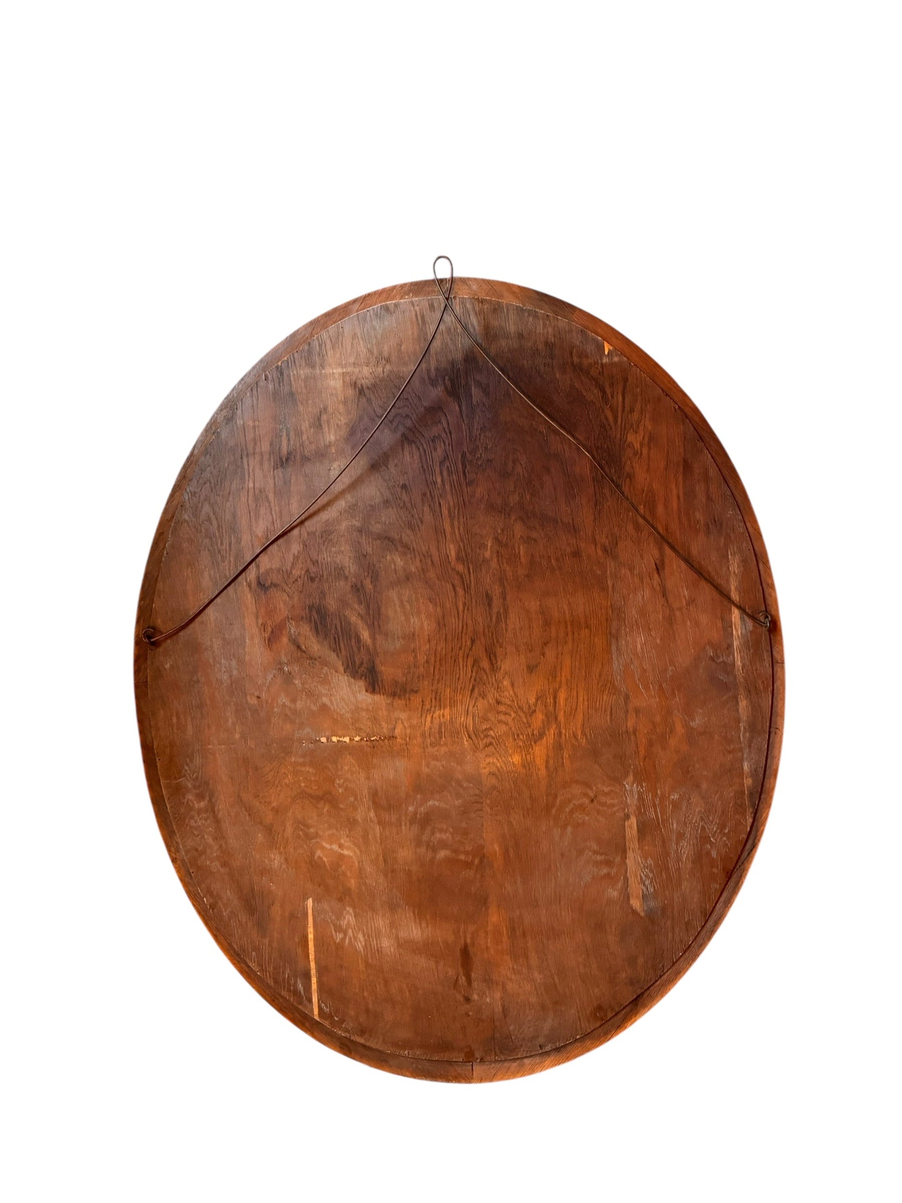 An oval-shaped mirror featuring a wooden frame and an ornate metal crest at the top.