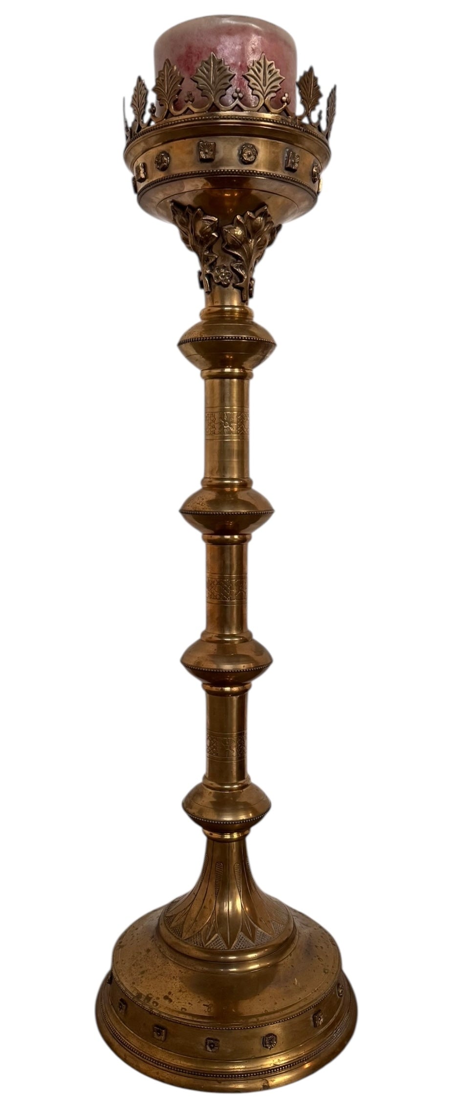 A tall, ornate, antique brass or bronze Gothic church candlestick holder with a pink candle in the top.