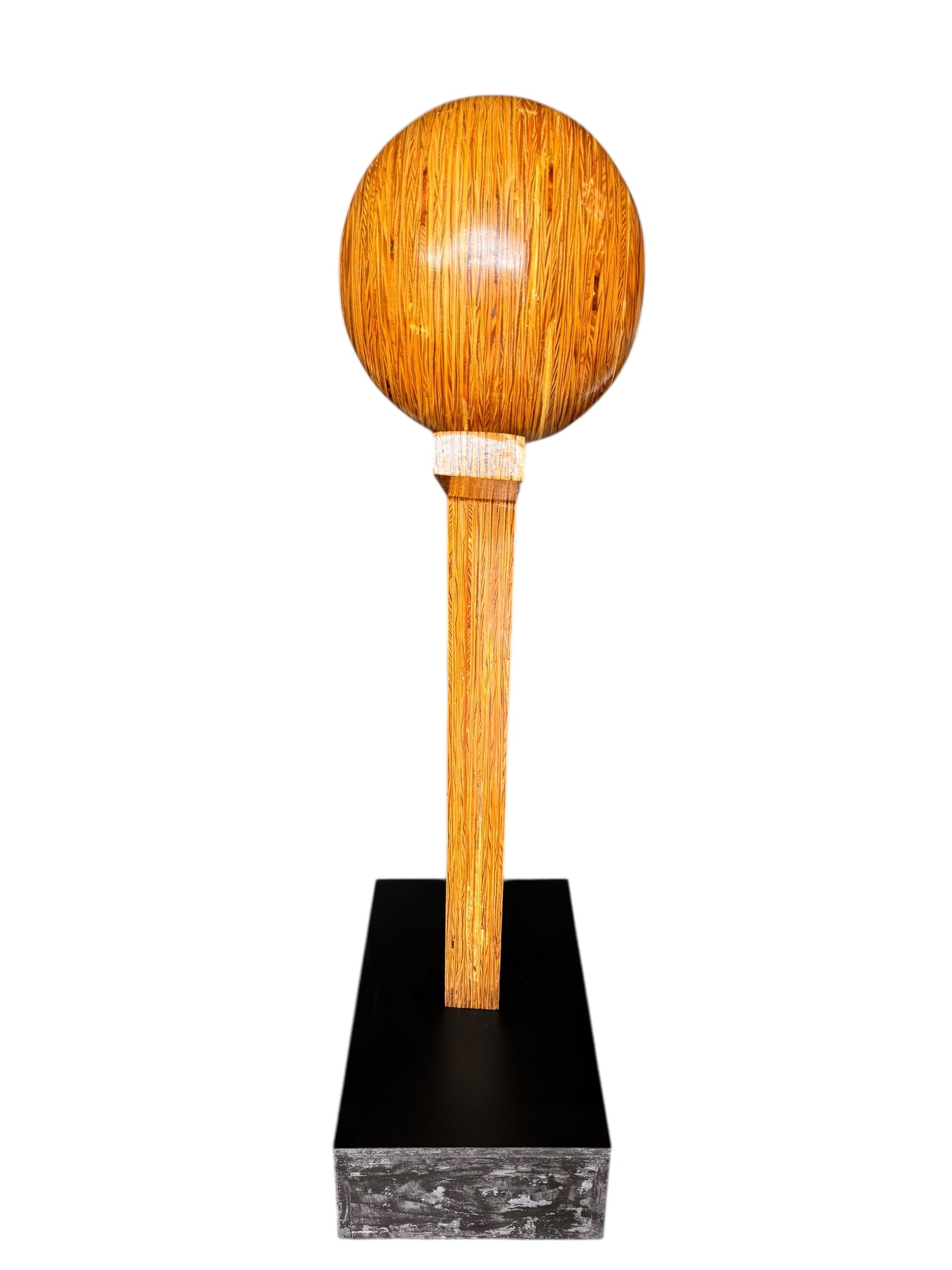 A wooden sculpture featuring a dark square base, a vertical trunk that branches into two angled supports, and a turned wooden sphere resting on the higher support.