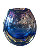 Sommerso glass vase with flattened sides creating a fish-eye effect, featuring cobalt and indigo colors and internal bubbles.