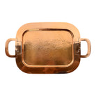 The set includes a large, rectangular, hammered copper tray with geometric openwork handles. Resting on the tray is a tall, slightly tapered copper coffee pot with a wooden handle, a matching smaller creamer pitcher with a similar wooden handle, a lidded sugar bowl, and a tiny matching metal cup or jigger. To the right off the tray sits a large, spherical copper water pitcher or jug with a wide mouth and ice lip.