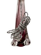 A tall, Mid-Century Modern sculptural table lamp featuring a hand-blown art glass base. The base is crafted in the Sommerso style, with a deep amethyst purple core encased in a thick, clear crystal outer layer that twists upward in an organic, fluid motion. The lamp is topped with a white, knife-pleated empire shade and a clear glass ball finial. The overall design is elegant and slender, emphasizing the contrast between the saturated purple glass and the transparent, light-refracting crystal.