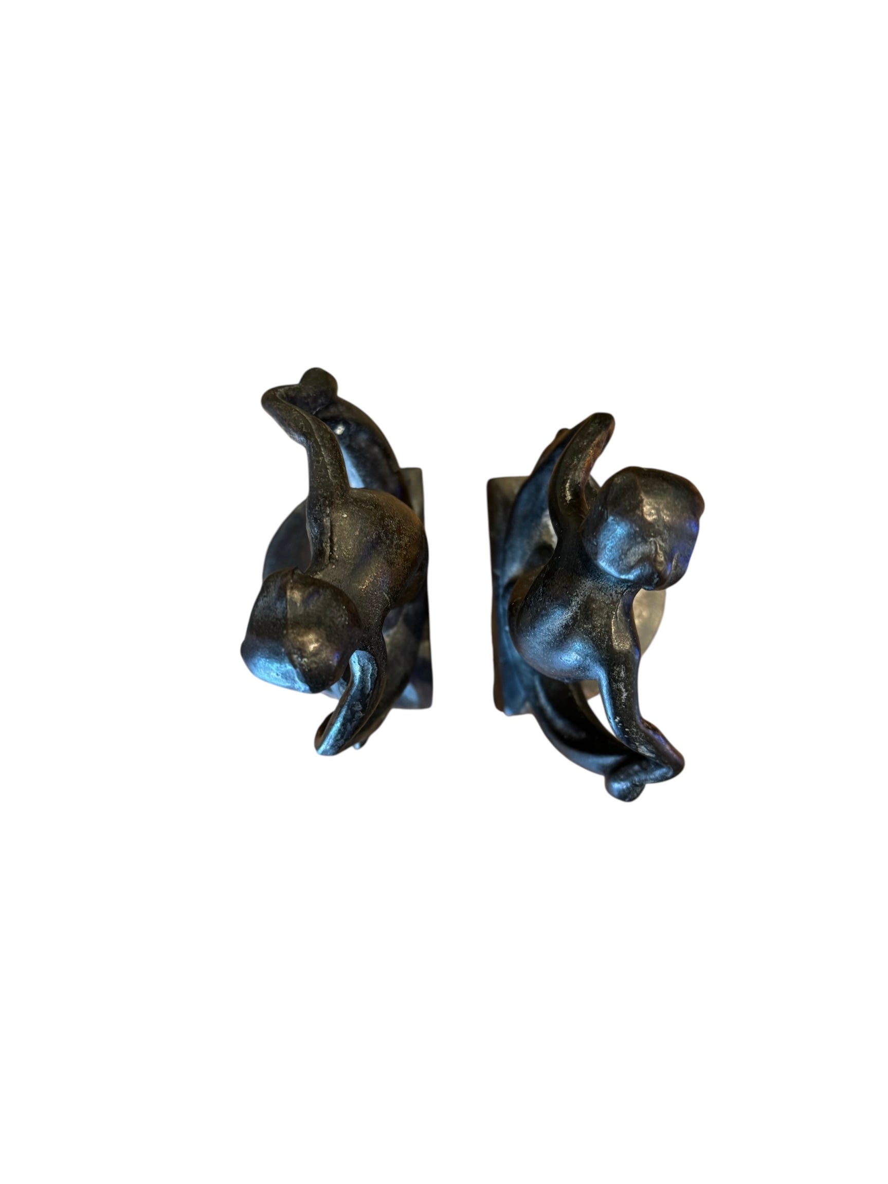 Two cast iron bookends in the Art Deco style. Each features a nude female figure leaning gracefully with one leg extended, posed atop a stylized wave or drape. The bookends have a bronze-colored finish and a vintage appearance.