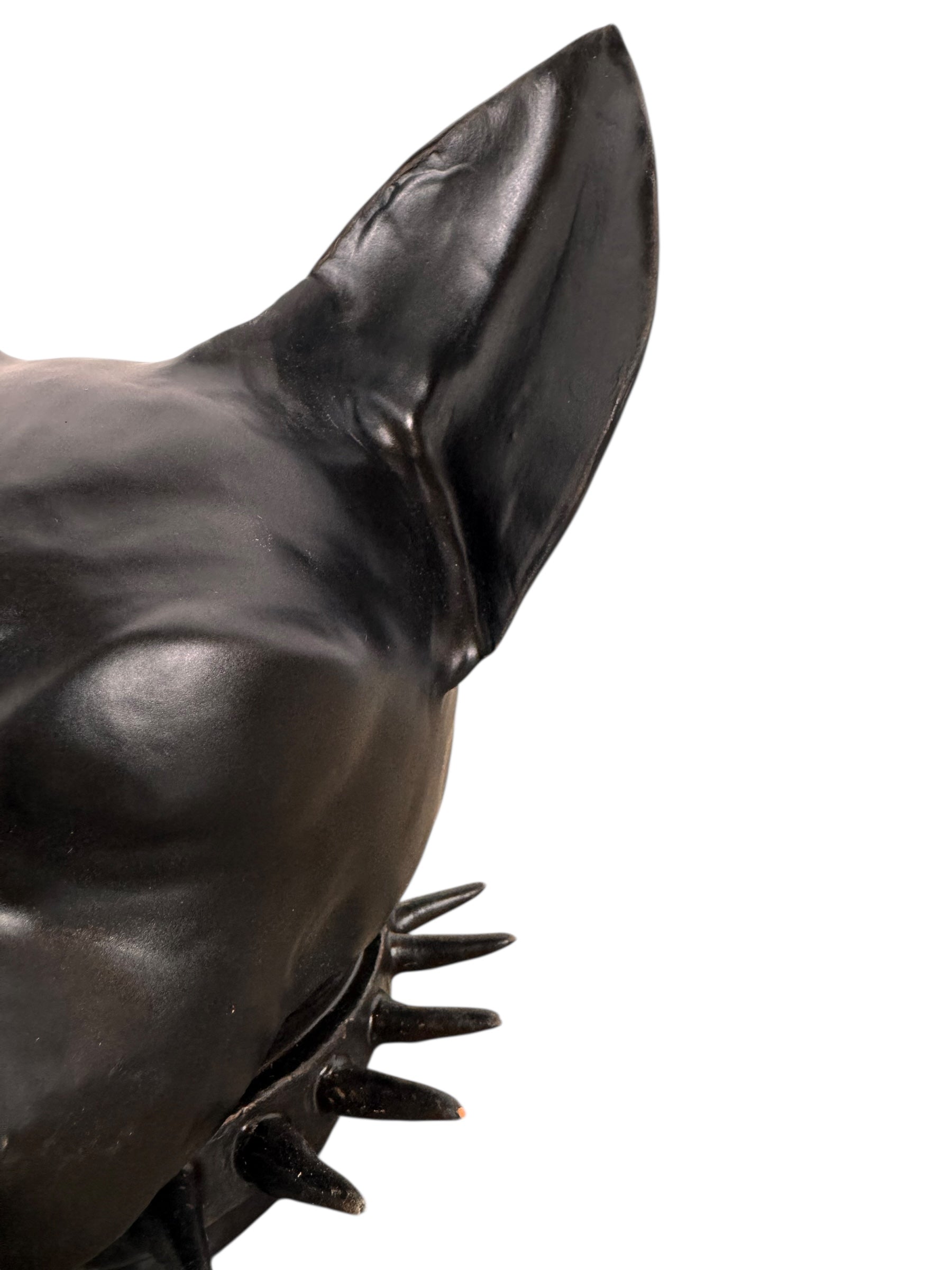 A smooth, dark black-colored ceramic sculpture of a Miniature Pinscher's head. The stylized dog features large, upright pointed ears and a prominent spiked collar around its neck. The surface has a soft sheen, with minimalist indentations for eyes and a rounded snout, creating a sleek and modern aesthetic.
