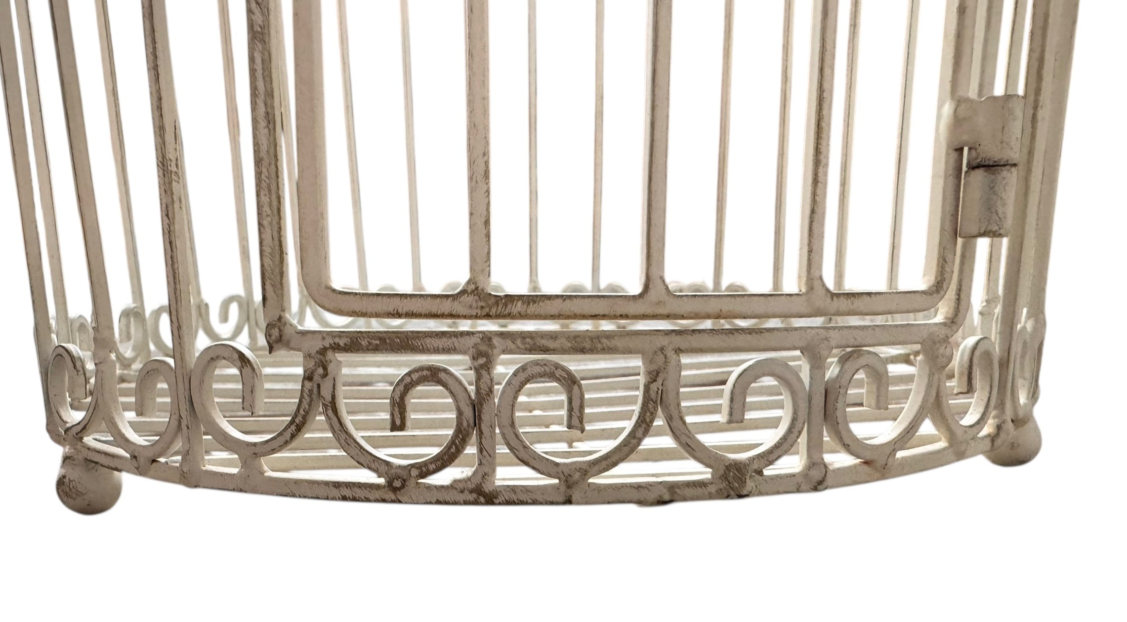 A single, white or cream-colored, decorative wrought iron bird cage with a hinged door and a hanging loop at the top. The cage has a vintage or antique style 