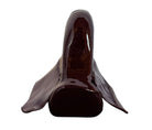 A glossy, dark chocolate brown ceramic bust of a Labrador dog. Created by Enza Fasano, the sculpture features a minimalist, stylized design with smooth, flowing lines and a high-shine glaze that reflects light. The dog’s long ears drape down the sides, and its snout is rounded, capturing the gentle essence of the breed in a contemporary Italian pottery style.