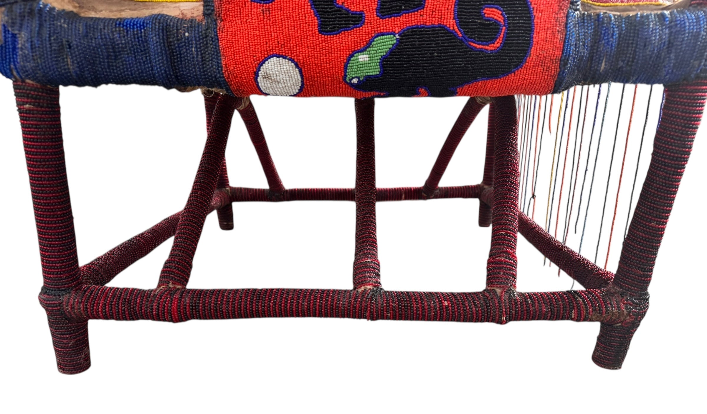 Close-up of a Yoruba beaded armchair, featuring vibrant red, blue, and green beads in a pattern of stylized masks and animals such as lions and zebras