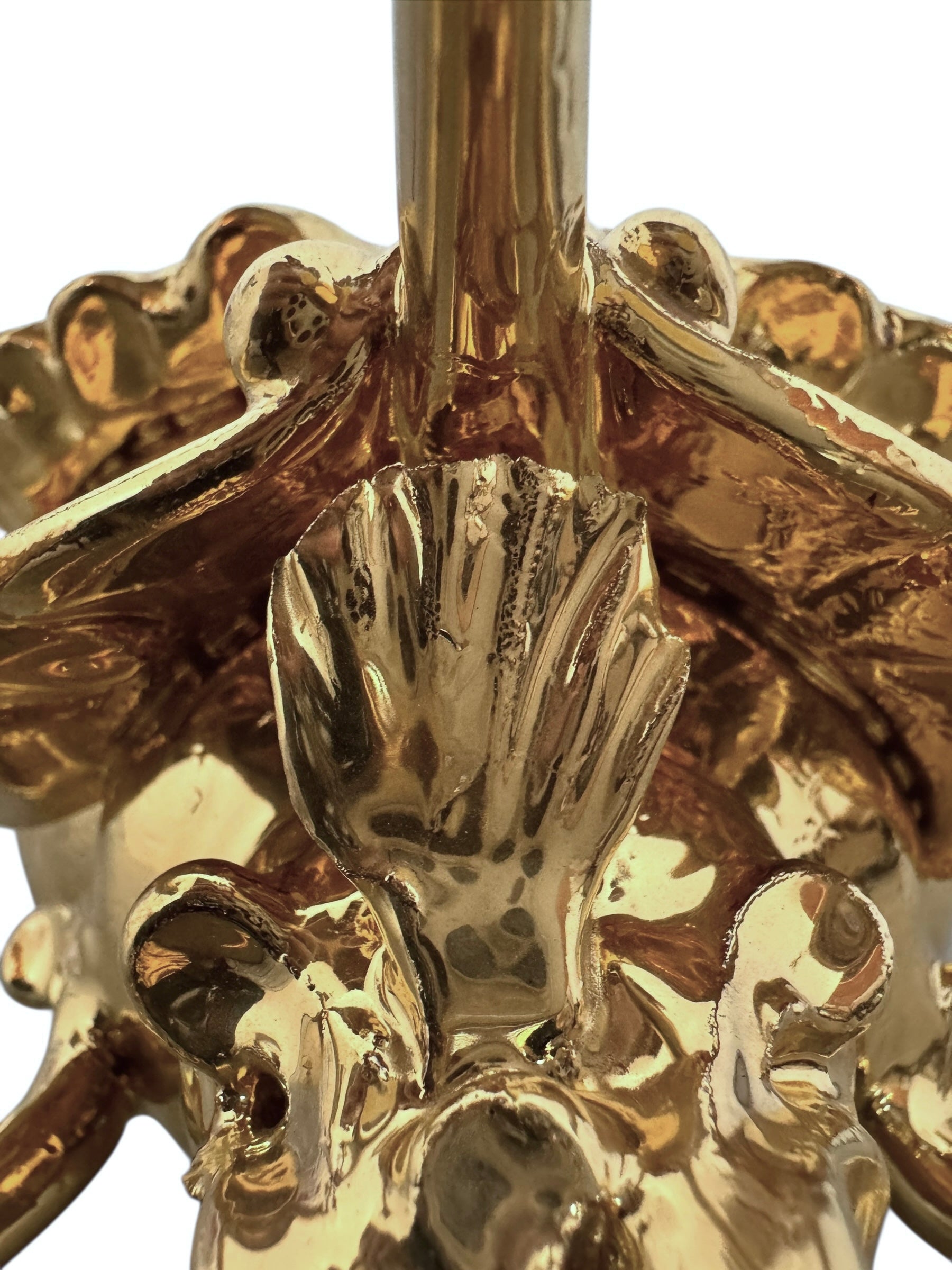 A handcrafted ceramic sculpture of a rhinoceros beetle by Enza Fasano, featuring a brilliant, high-gloss gold metallic finish. The beetle is captured in a dynamic, slightly upturned pose with detailed textures on its ribbed shell and prominent, curved horns. The piece reflects light across its polished surface, showcasing the artist’s signature fusion of traditional Pugliese pottery and contemporary luxury.