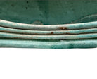 curved ceramic piece resembling a green pod, supported by a block plinth. The seafoam-green ceramic structure extends wide on either side, curving upward to form a wavy, boat-like shape. The outer surface is dotted with rows of small, raised, brown-orange, acorn-like protrusions. The top rim is layered with parallel, grooved ridges. The base is a vertical rectangular block with a heavily textured, bark-like surface in a dark green and black finish.