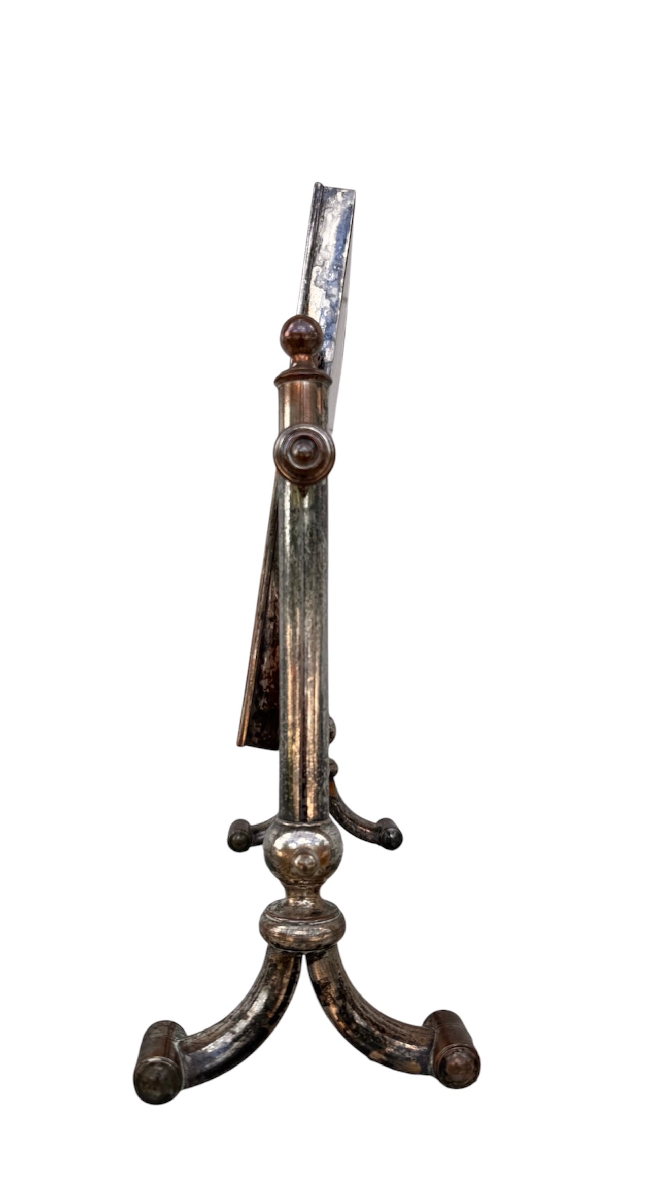 The antique Chevalier Mirror features a rectangular swing frame supported by two turned posts on decorative trestle feet. The mirror stands on four scrolled feet and features its original tarnished, silvered finish. The front of the mirror reflects a bright blue sky with wispy white clouds. The original dark brown backing is still attached to the frame.