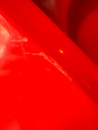 A top-down, straight-on view of a vintage, high-gloss cherry red bathtub. The tub basin is molded into a distinct double-tiered heart shape, with a shallower outer heart cascading into a deeper, smaller inner heart basin centered within a wide rectangular red deck.