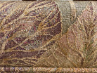 A Neoclassical-style wooden loveseat with a dark mahogany frame featuring scrolled arms and tapered legs. The upholstery consists of plush cushions and two matching cylindrical bolster pillows, all covered in a golden-yellow jacquard fabric with a large-scale, repeating autumnal leaf pattern in shades of muted orange and brown.