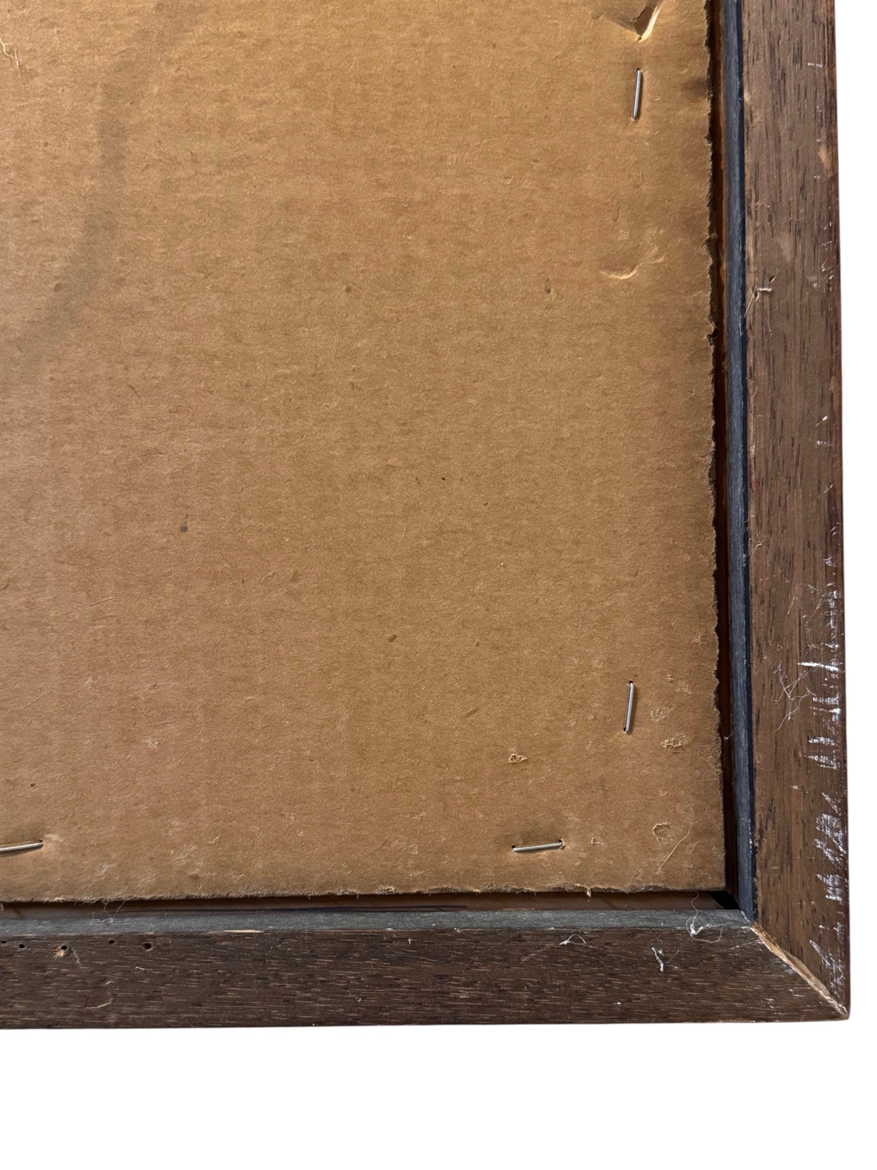 Close-up of a wooden picture frame corner with brown cardboard backing.