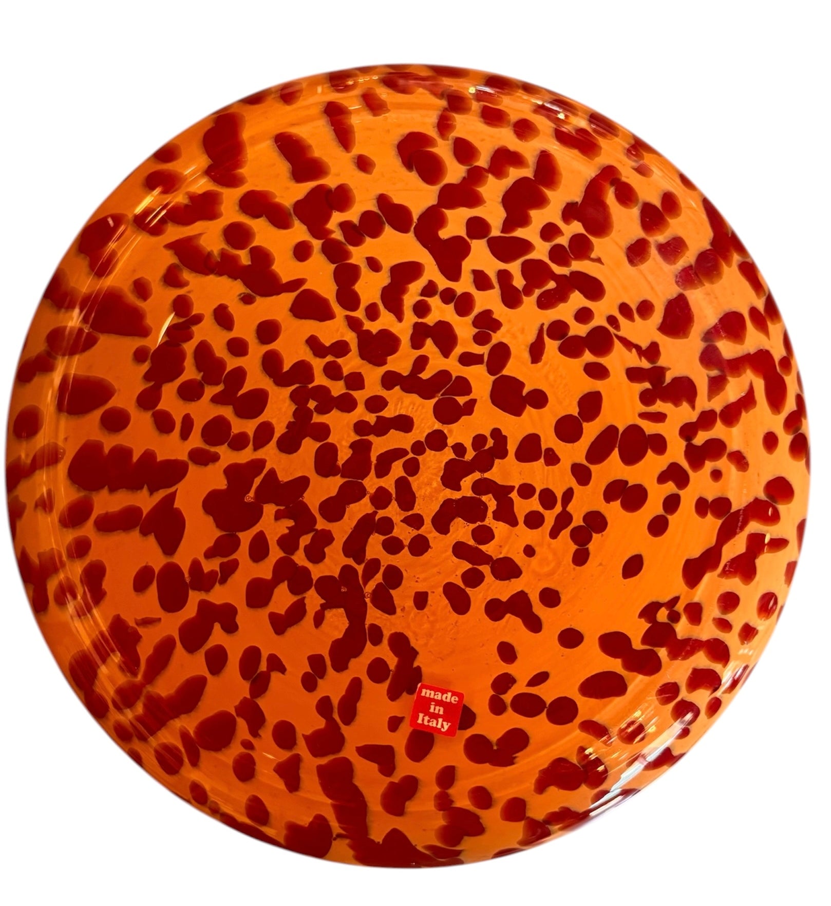 A hand-blown Italian Murano glass vase featuring a wide, bulbous body and a short, flared rim. The glass is a vibrant, translucent amber-orange base decorated with an organic "macchia" or spotted pattern of deep ruby red blotches. The red spots are elongated and vertical near the neck, becoming larger and more rounded toward the base. The surface has a high-gloss, reflective finish, showcasing mid-century modern craftsmanship.
