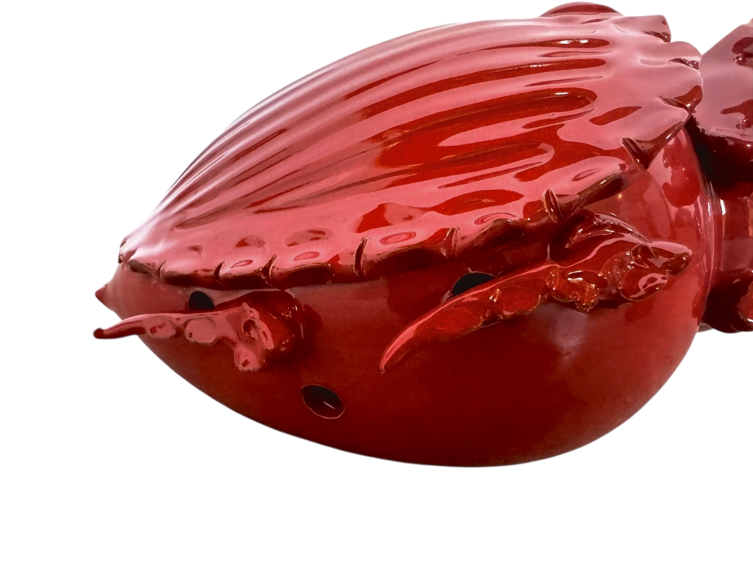 A vibrant, glossy red ceramic sculpture of a rhinoceros beetle by Enza Fasano. The piece features a highly reflective, deep crimson glaze that accentuates its smooth, rounded abdomen and the intricate, jagged textures of its head and horns.