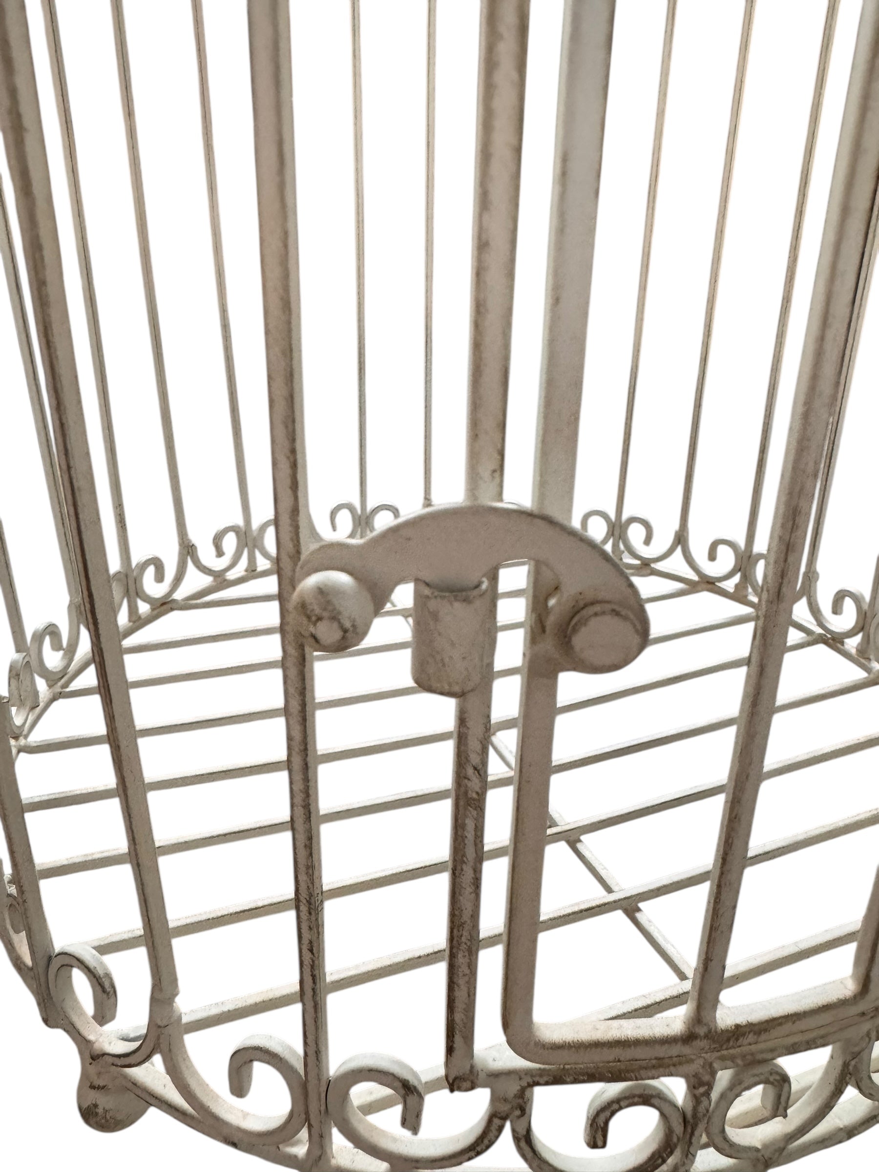 A single, white or cream-colored, decorative wrought iron bird cage with a hinged door and a hanging loop at the top. The cage has a vintage or antique style 
