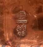 The set includes a large, rectangular, hammered copper tray with geometric openwork handles. Resting on the tray is a tall, slightly tapered copper coffee pot with a wooden handle, a matching smaller creamer pitcher with a similar wooden handle, a lidded sugar bowl, and a tiny matching metal cup or jigger. To the right off the tray sits a large, spherical copper water pitcher or jug with a wide mouth and ice lip.