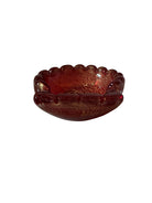 A handcrafted Murano glass bowl with a ruffled edge, deep red color, and gold specks created using the "oro zecchino" technique. The surface has a crackled gold pattern that reflects light, making it a striking decorative piece.
