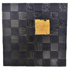 A triptych of abstract paintings featuring a grid pattern of textured black squares by Sabine Stromeyer called “Square One”. The left and right panels each have a single vertical gold rectangle in the center, while the middle panel has two stacked gold rectangles in the center.