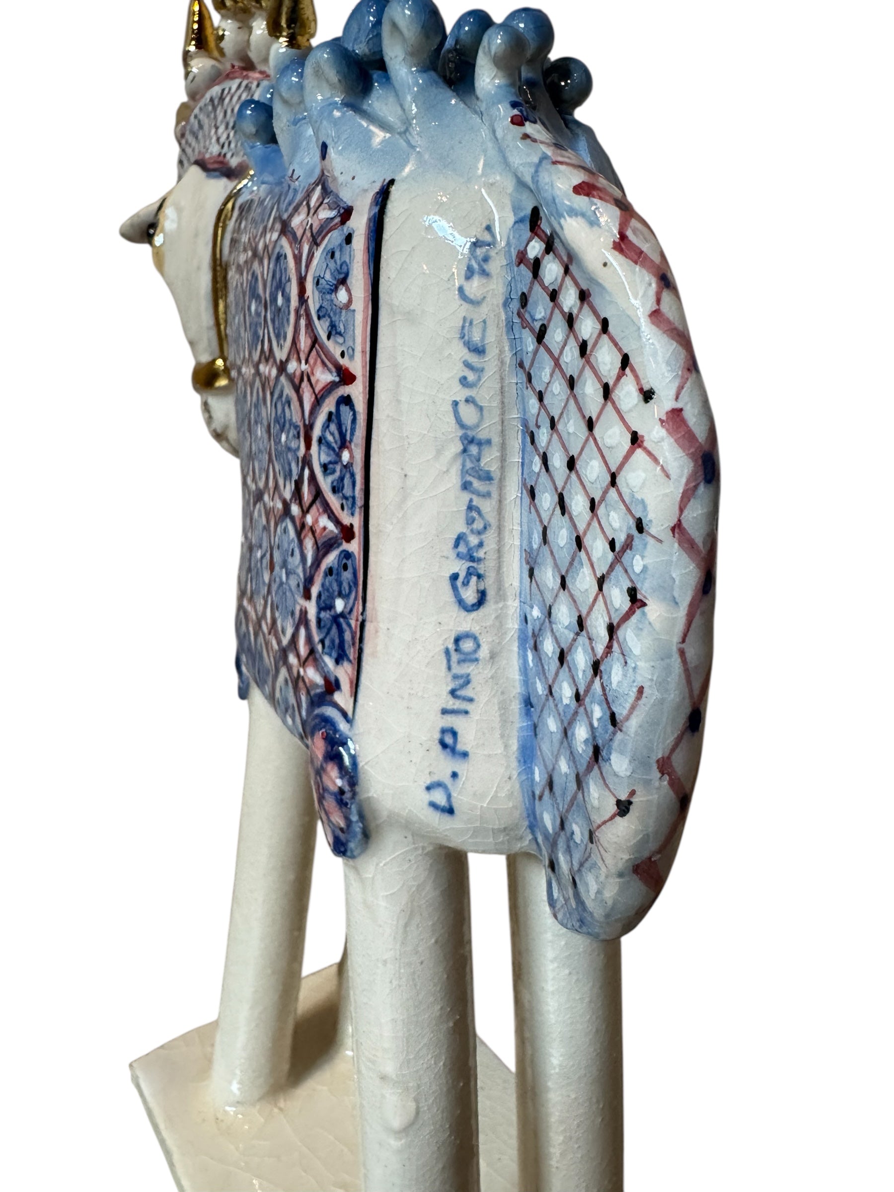 Ceramic horse by Domenico Pinto, featuring a white glazed body, geometric quilting on the saddle, a decorative crown with white and gold accents, and 24Kt gold detailing. The horse stands on four legs and is placed on a white base.