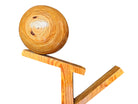 A wooden sculpture featuring a dark square base, a vertical trunk that branches into two angled supports, and a turned wooden sphere resting on the higher support.