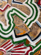 A close-up, angled view of an abstract oil painting titled 'Topography' by Robert Wymer. The painting's edge reveals thick, textured swirls of brown, gold, red, green, and white paint. It is framed in a natural light-brown teak wood frame, with a visible corner joint where two pieces of wood meet