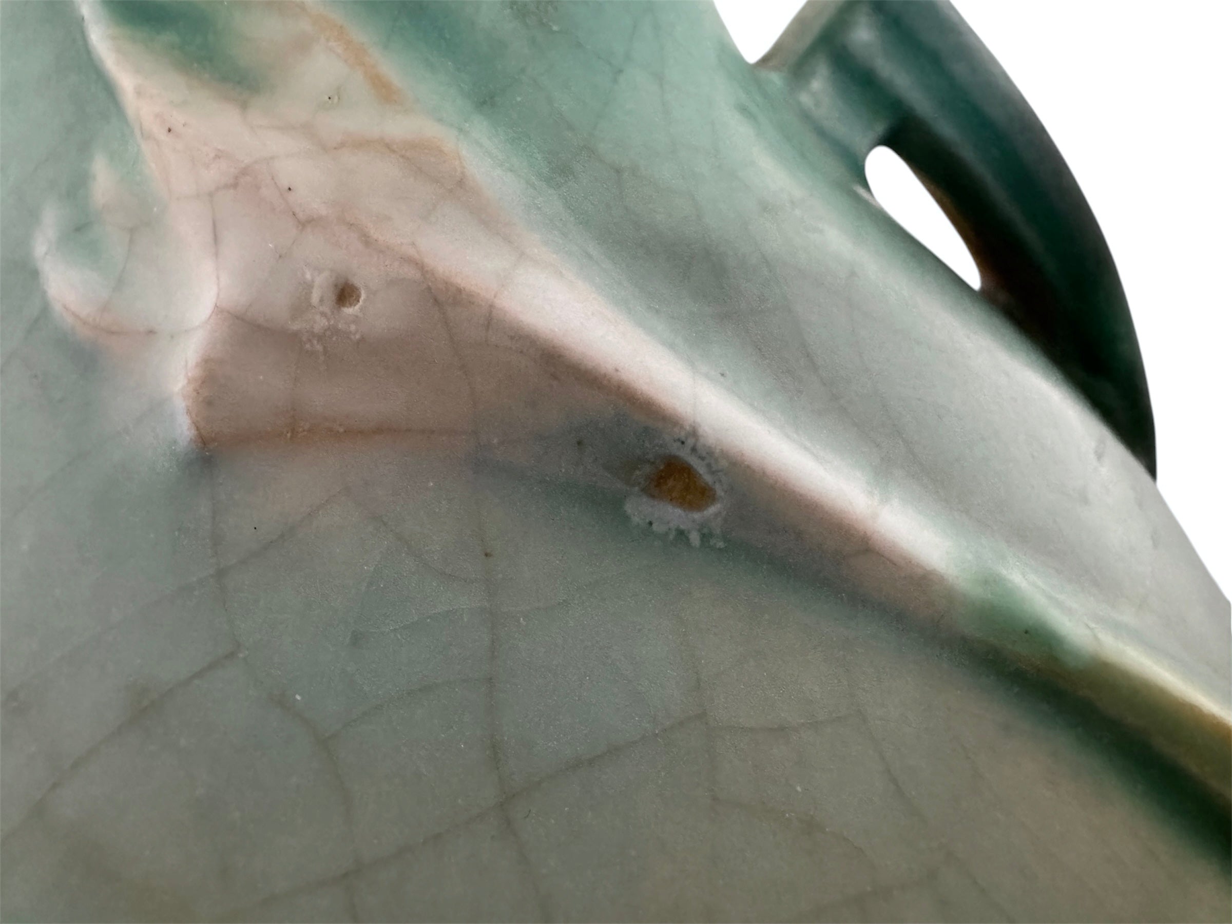 A squat, rounded vintage Roseville pottery vase in a light teal-blue matte glaze. The vase features two small, angular geometric handles on its shoulders and a flared rim. Embossed on the front is a cluster of textured, green and pale-yellow thornapple blossoms tucked against sharp, serrated green leaves. The surface shows a subtle, fine network of age-related crazing lines throughout the glaze.
