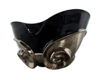 A large, decorative ceramic bowl by Dolbi Cashier in a dramatic Postmodern style. The top half is finished in a polished, piano-black glaze with an organic, wavy "butterfly" rim that dips in the center and rises at the sides. The bottom half is finished in a reflective, metallic silver chrome glaze, featuring bold, geometric-rounded feet and a structured base that appears to "hold" the black vessel. The overall shape is wide and sculptural, reminiscent of 1980s Art Deco Revival.