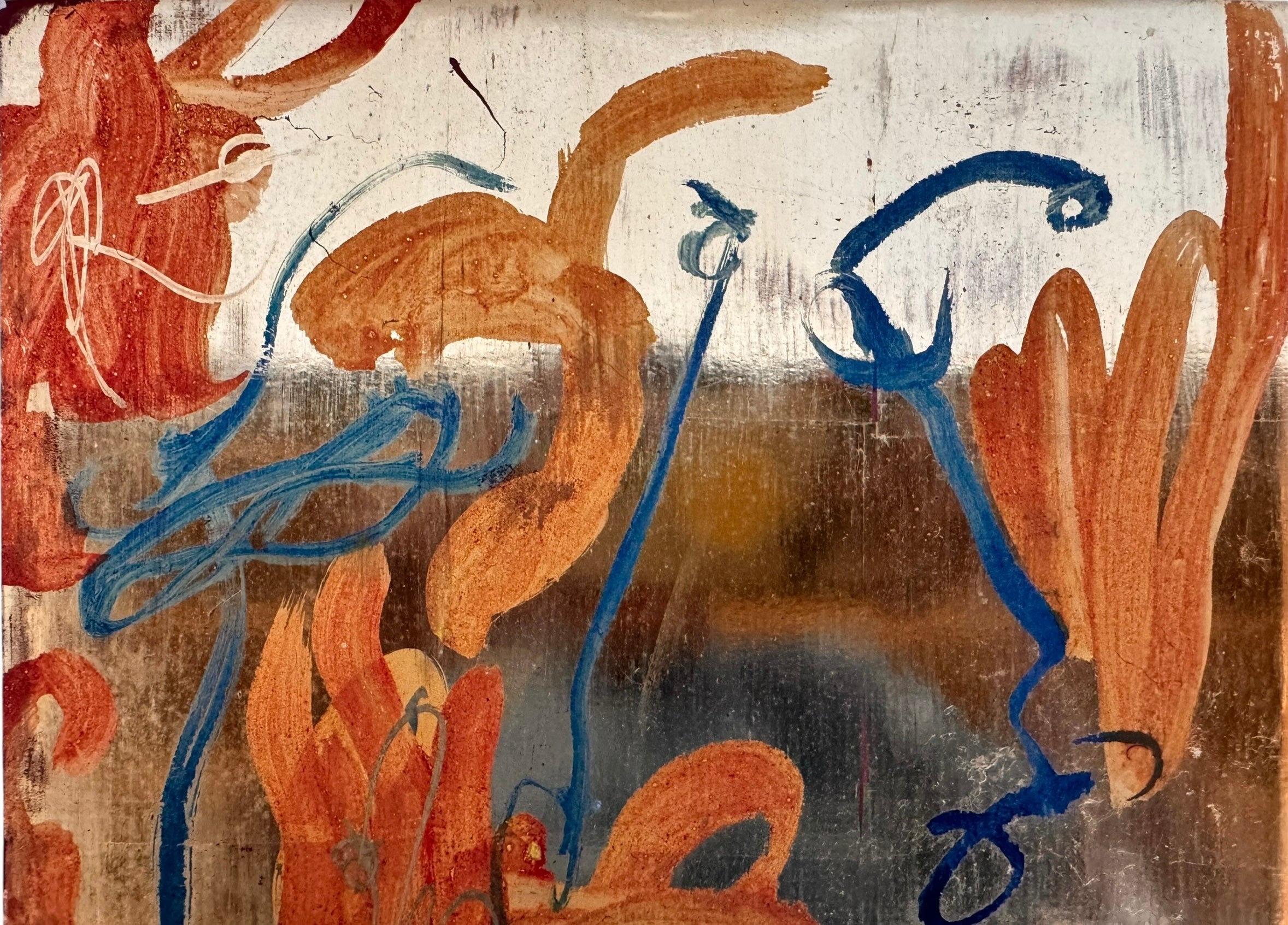 An abstract mixed-media painting on a vertical rectangular panel with a reflective, metallic gold and copper background. The composition features fluid, expressive brushstrokes in warm orange, ochre, and deep blue.
The orange strokes are thick and organic, resembling swirling flames or floral petals, while the blue marks consist of thin, lyrical lines and looped scribbles that dance across the surface. The metallic substrate is visible through the translucent paint, creating a play of light and texture