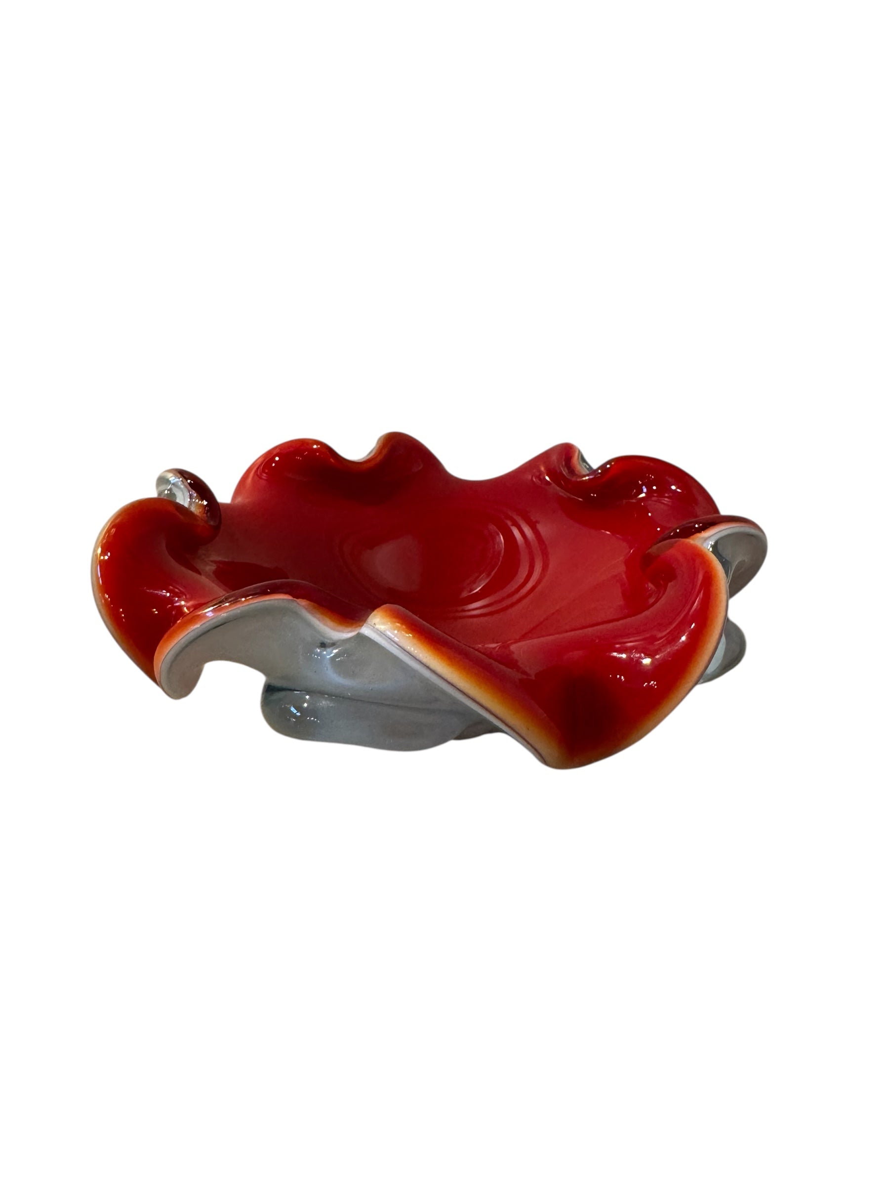 A Murano art glass bowl featuring a vibrant red interior encased in white glass, with a decorative ruffled edge. The piece is handblown, showcasing the Incamiciato technique.