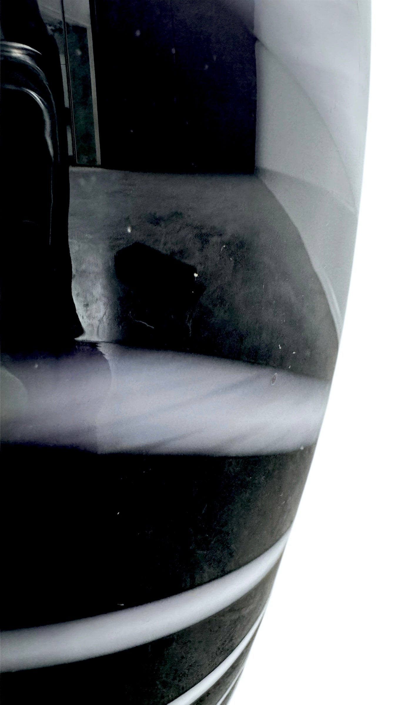 A sleek, hand-blown Polish art glass vase featuring a tall, slender neck that flares into a rounded, bulbous body. The vase is made of opaque black glass decorated with a continuous white spiral ribbon that winds around the entire piece from base to rim. The high-gloss, reflective surface creates sharp highlights, emphasizing its smooth, sculptural silhouette against a plain white background.
