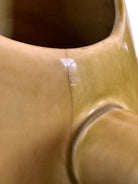 A chartreuse (yellow-green) ceramic pitcher designed by Russel Wright, featuring a teardrop shape, an elongated spout, and a curved handle