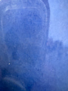 A Russel Wright American Modern stoneware water pitcher in a glossy Manitoga blue glaze is centered against a white background. The pitcher has a teardrop shape, a large handle, and a wide spout