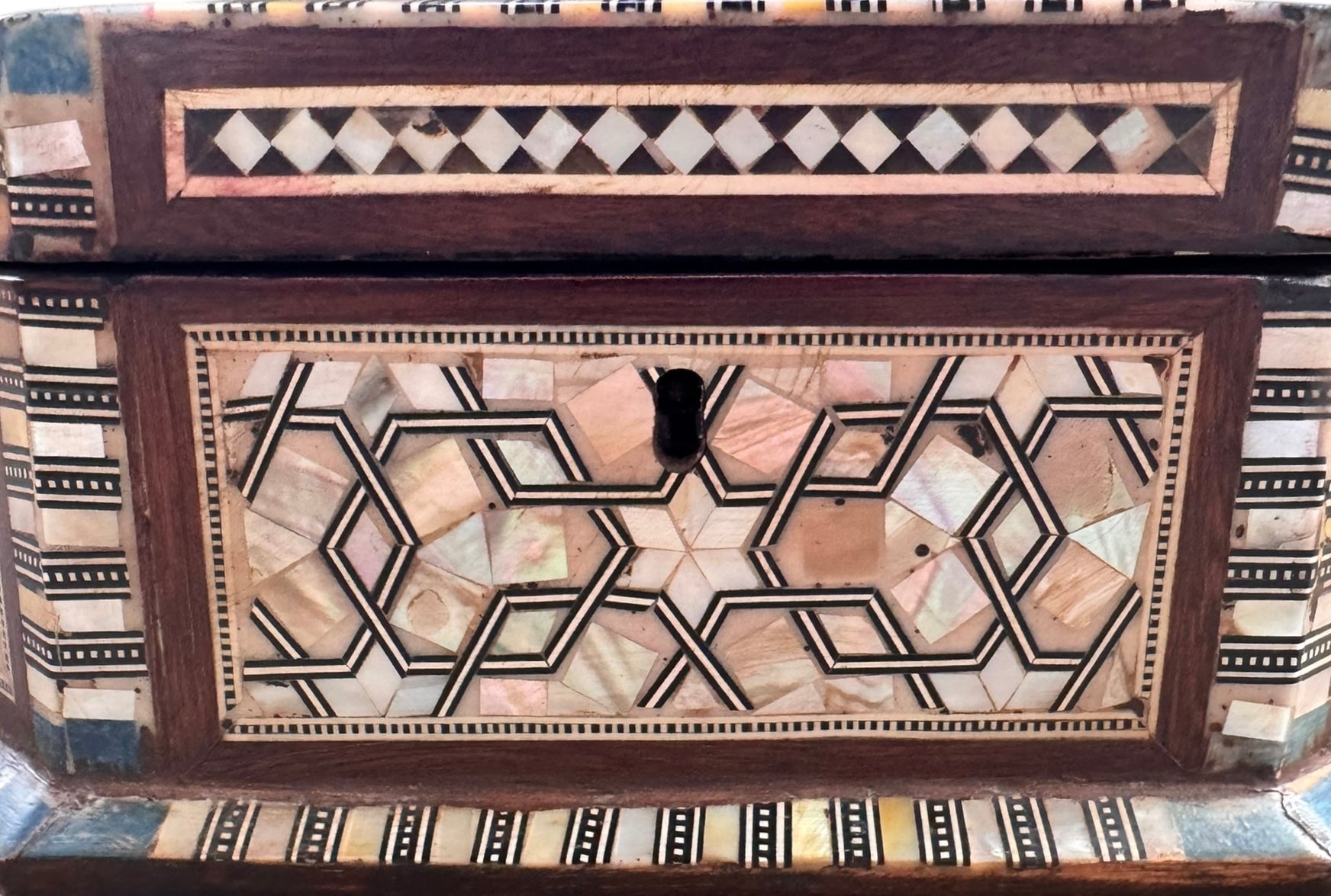 An ornate octagonal Syrian inlaid box, intricately decorated with geometric patterns made from dark wood, iridescent mother-of-pearl, vibrant abalone shell, and pale bone