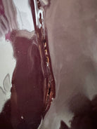 A glossy, dark chocolate brown ceramic bust of a Labrador dog. Created by Enza Fasano, the sculpture features a minimalist, stylized design with smooth, flowing lines and a high-shine glaze that reflects light. The dog’s long ears drape down the sides, and its snout is rounded, capturing the gentle essence of the breed in a contemporary Italian pottery style.