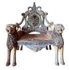 A pair of antique, heavily carved Anglo-Indian style throne chairs featuring lion figures as legs and arm supports, and peacock motifs on the backrests. The chairs have a distressed, multi-colored painted finish.