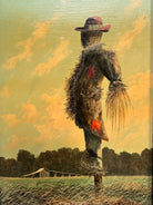 An oil painting on a wooden panel depicts a solitary scarecrow standing in a vast, grassy field under a pale yellow and blue sky. The scarecrow is shown from a three-quarters back view, wearing a brimmed hat and a tattered, patched brown coat with frayed straw bursting from its sleeves and edges. In the far left background, a long, white rustic barn sits before a dense line of green trees. The entire piece is enclosed in a thick, weathered, natural wood frame.