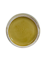 A chartreuse (yellow-green) ceramic pitcher designed by Russel Wright, featuring a teardrop shape, an elongated spout, and a curved handle