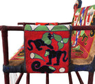 Close-up of a Yoruba beaded armchair, featuring vibrant red, blue, and green beads in a pattern of stylized masks and animals such as lions and zebras