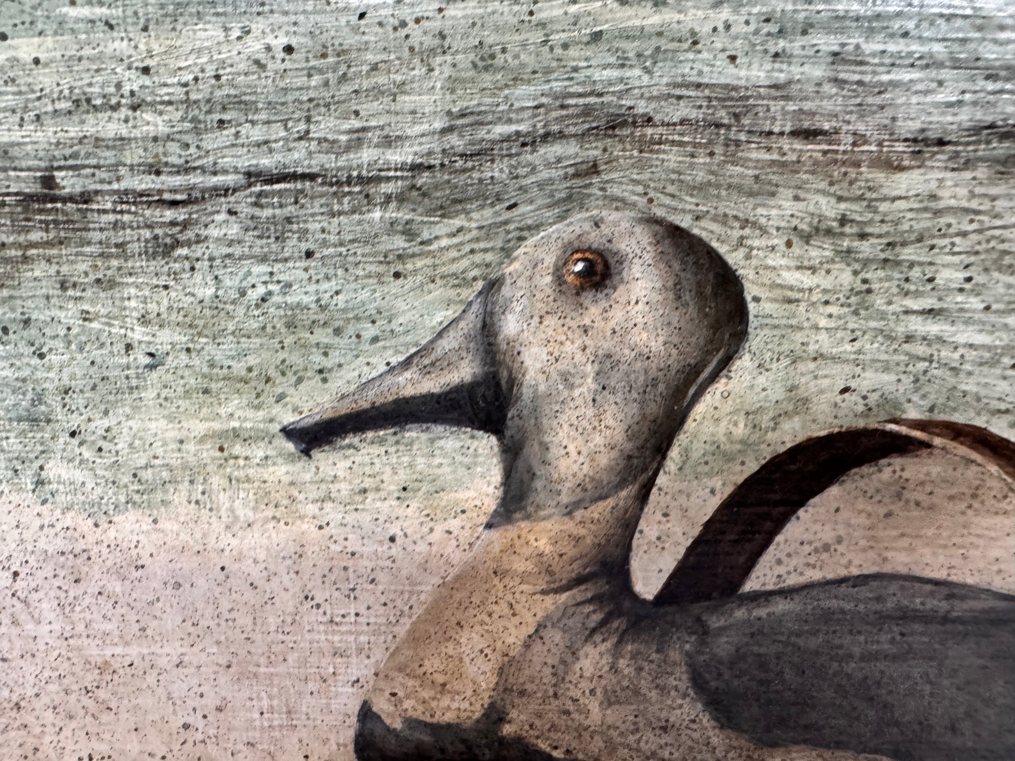 A realistic painting of a rustic interior scene by Travis Whitfield. A duck sits inside a woven basket on a dark wooden table with a single drawer. A French horn hangs on the light blue and white log wall behind the table. A multi-pane window on the left side of the painting shows an outdoor view. 