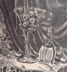A black-and-white lithograph titled Victoria by the artist Zsissly. A woman with a veil over her dark hair sits directly facing the viewer behind a highly detailed, round dining table crowded with objects. Every inch of the scene is densely textured, depicting a bowl of bananas and grapes, an ice bucket with wine bottles, crystal glassware, a decanter, and a patterned lace tablecloth. The background features intricate floral wallpaper, a paneled door, and heavy drapes. The style is eerie and densely shaded 