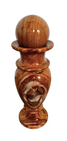 An elegant, hand-carved decorative vase made of polished Pakistani brown onyx. The vase features a classic, rounded urn shape with a tiered, flared neck and a solid matching spherical stone stopper resting on top. The stone displays rich, natural horizontal banding and swirling patterns in shades of honey, deep amber, rust-red, and cream. It stands on a small, integrated pedestal base against a clean white background, reflecting a high-gloss, mirror-like finish.