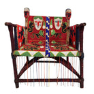 Close-up of a Yoruba beaded armchair, featuring vibrant red, blue, and green beads in a pattern of stylized masks and animals such as lions and zebras