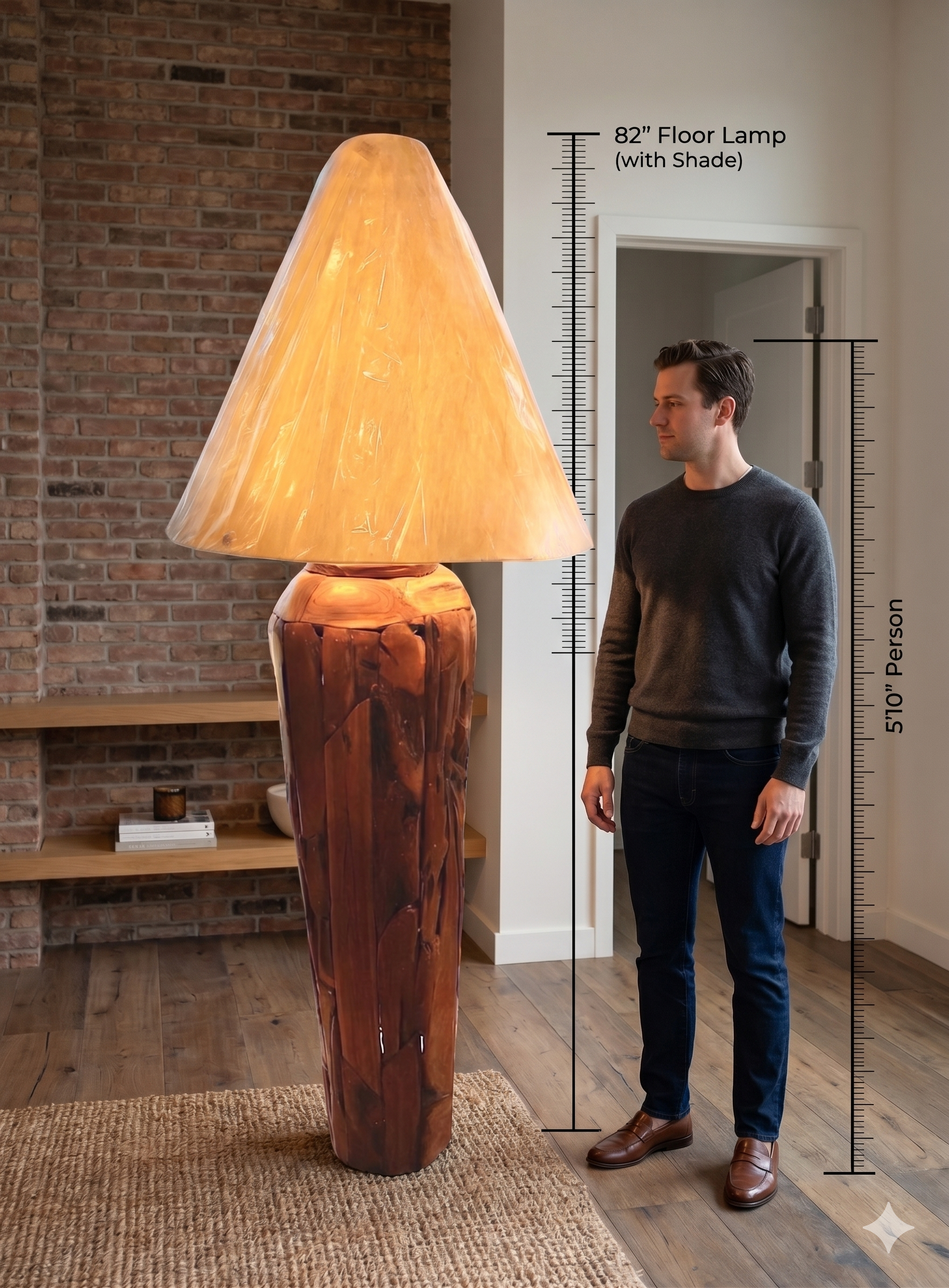 Two table lamps made from repurposed teak wood vases. The bases are tall and tapered, featuring a rugged, mosaic-like texture composed of various pieces of dark, polished teak wood with visible natural grain and crevices. Each lamp is topped with a large, warm-toned conical shade that is currently wrapped in protective clear plastic, emitting a soft, golden glow. The lamps are positioned on a clean white surface against a neutral background.
