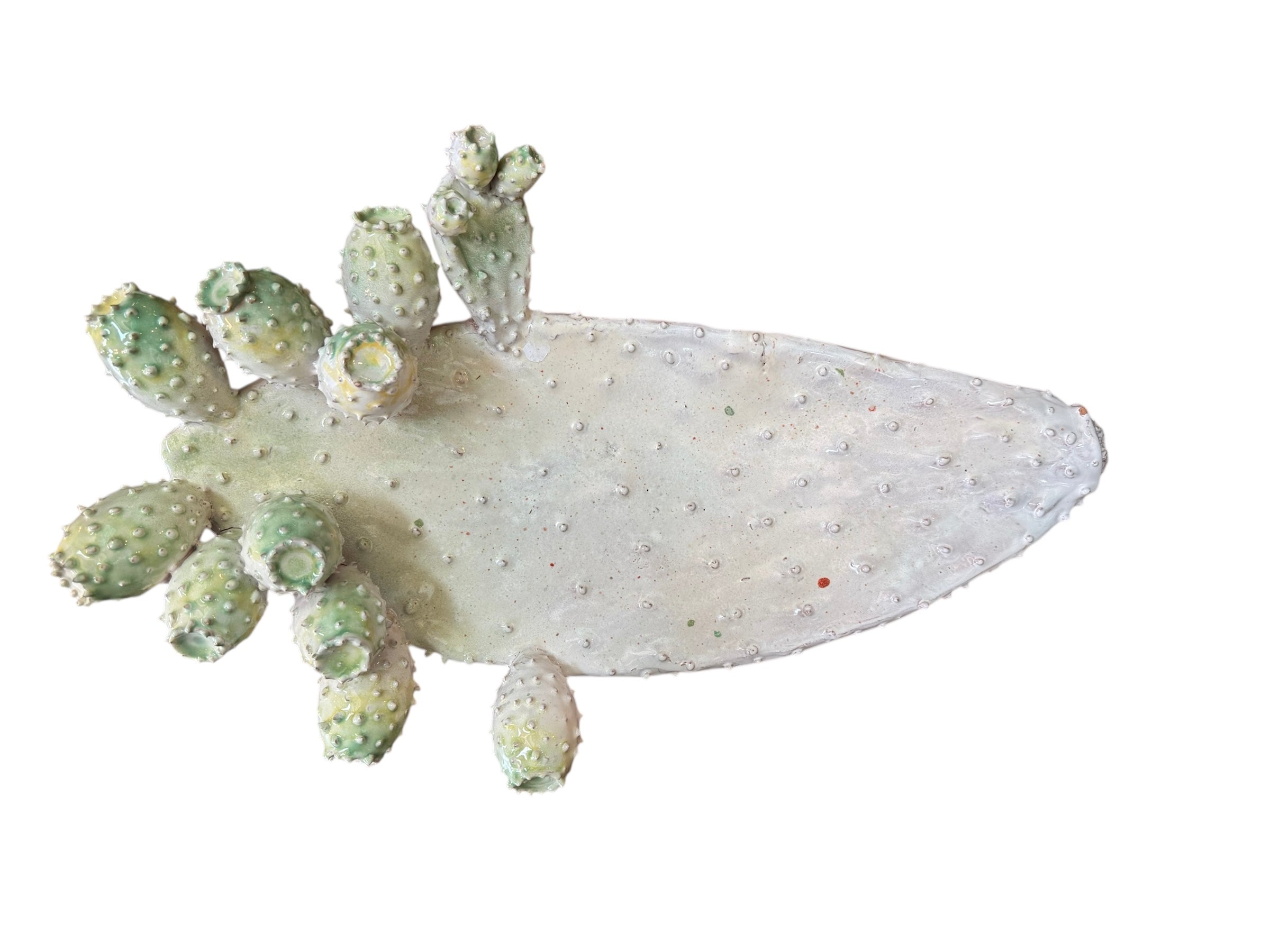 A white and green, glazed ceramic platter in the shape of a prickly pear cactus pad with attached prickly pear fruit. The surface has raised dots representing spines. 

Handmade White Cactus Platter with Green Accents- Italian Design by Enza Fasano Ceramiche
